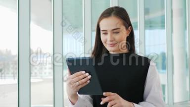 成功的女商人在办公室里用平板电脑，女商人在窗口附近<strong>营业</strong>，开心地微笑着机场